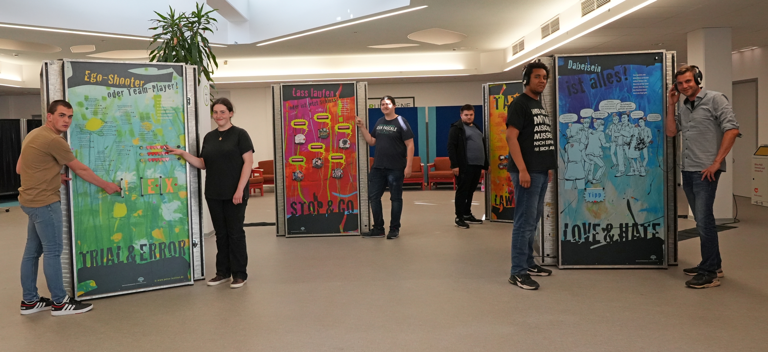 Jugendliche aus dem bbw Südhessen stehen an den Ausstellungs-Aufstellern der Ausstellung echt Krass